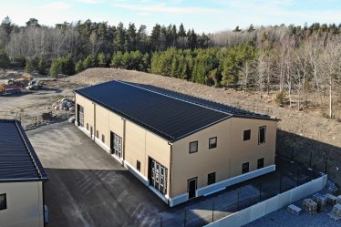 Stor gul industrifastighet framför skogsparti.
